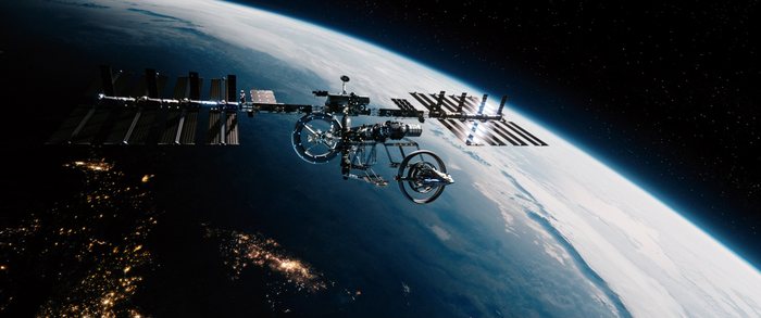 A space station in orbit above Earth, city lights across the night side below.